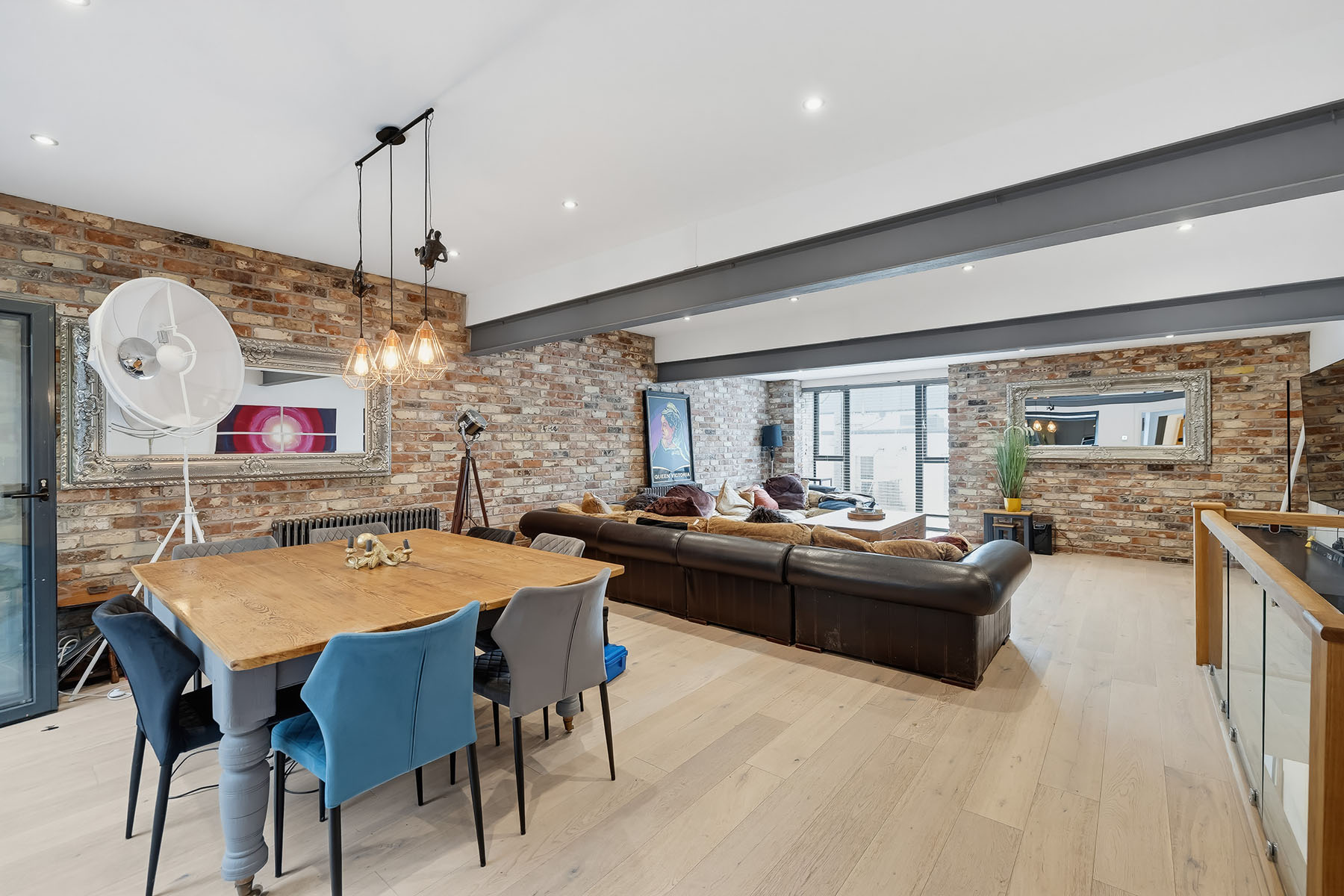 Open-plan dining and living space with exposed brickwork, wooden dining table and contemporary furniture