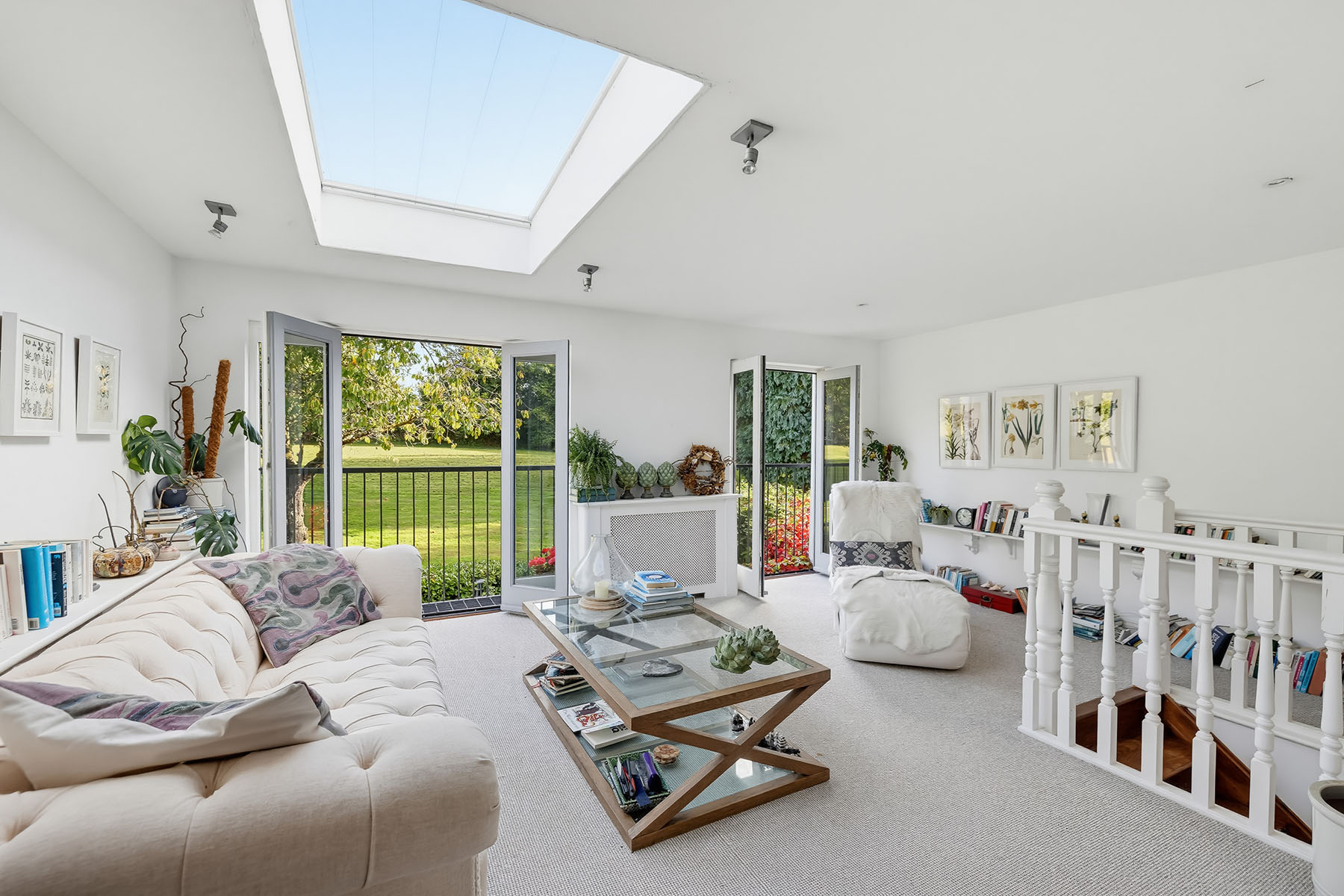 Bright living room with white sofa, rooflight and French doors overlooking a garden