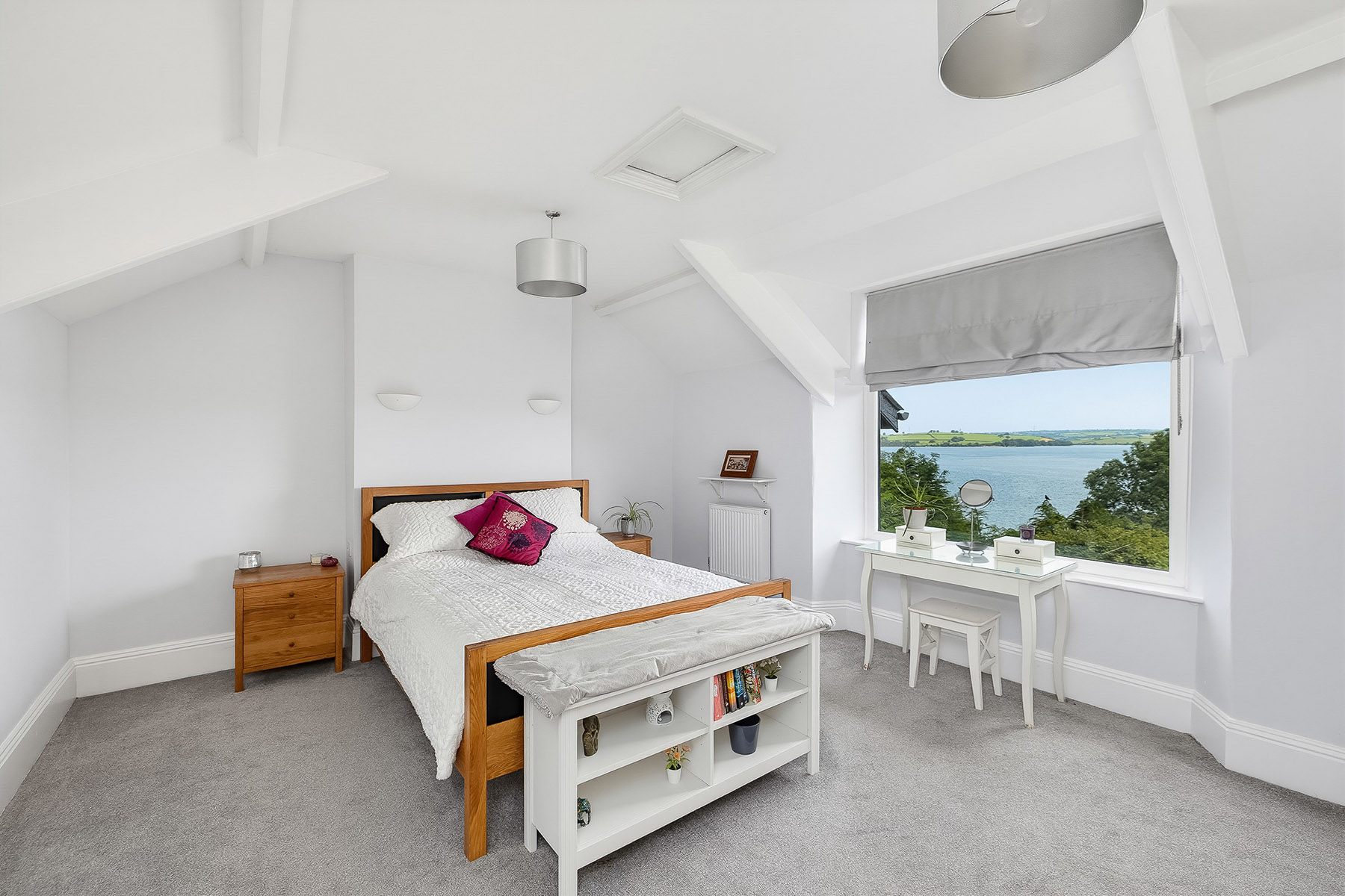 Bright, professionally photographed bedroom with a coastal view through the window