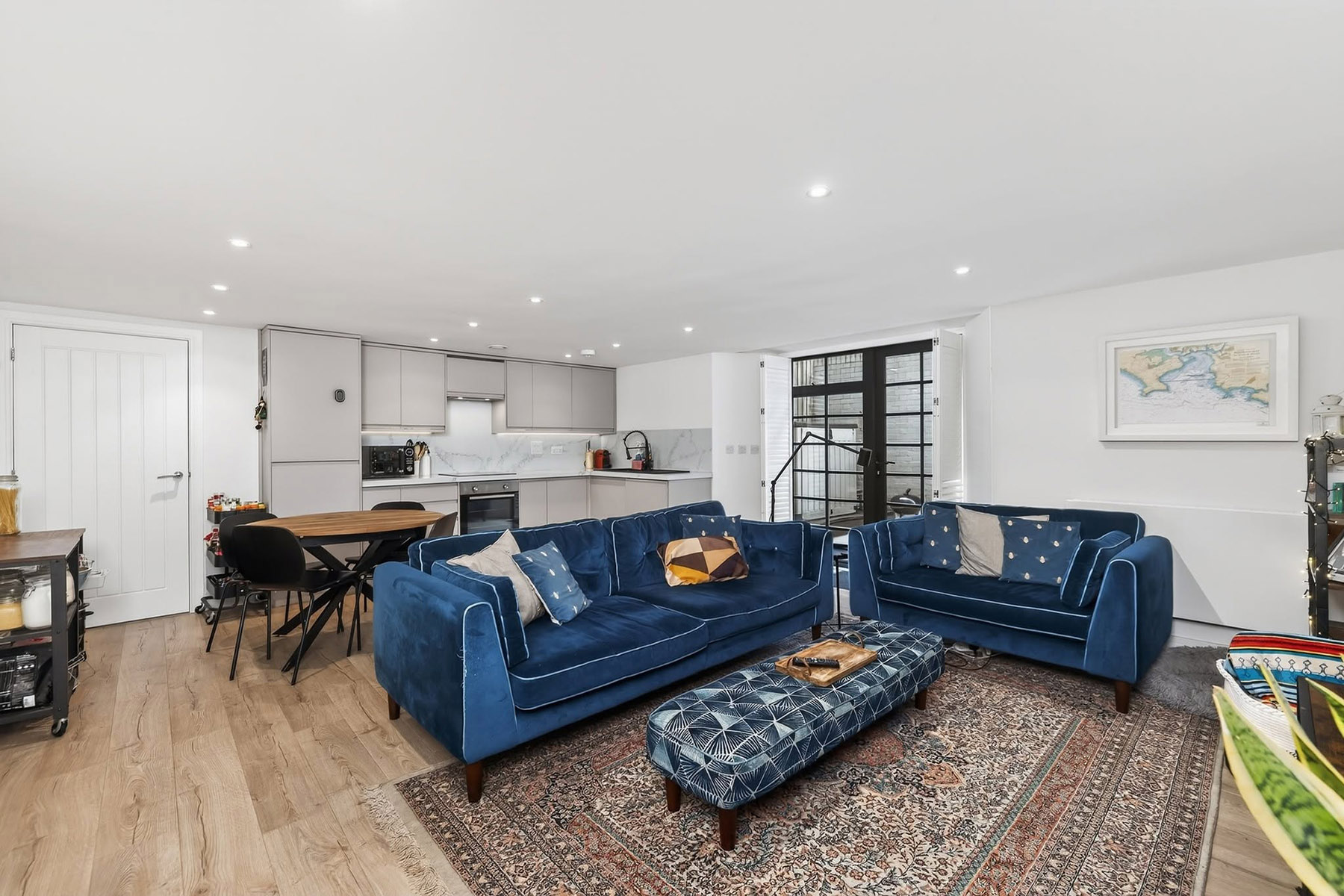 Professionally photographed version of the same open-plan kitchen and sitting room with blue sofas, balanced colour and more controlled perspective